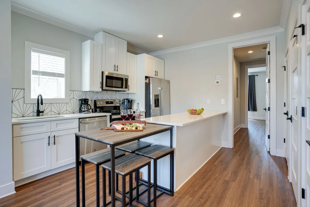 A vibrant kitchen scene focusing on the kitchen island, gleaming stainless steel appliances, and a geometric backsplash. The area is styled for entertaining, with ample counter space and modern amenities.